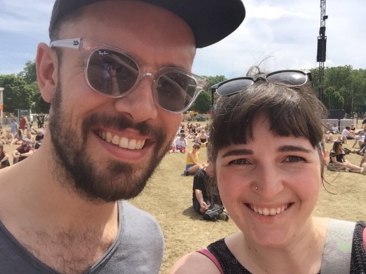 Two people smiling at a camera taking a selfie outside.
