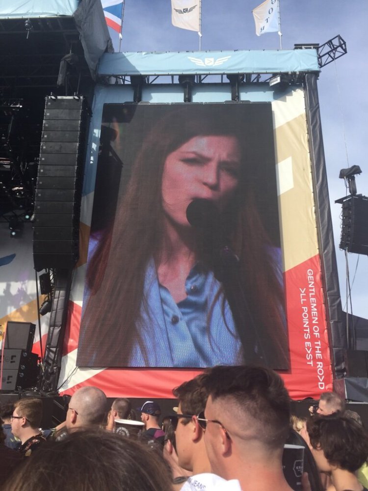 Singer Jade Bird on a large screen next to a stage/