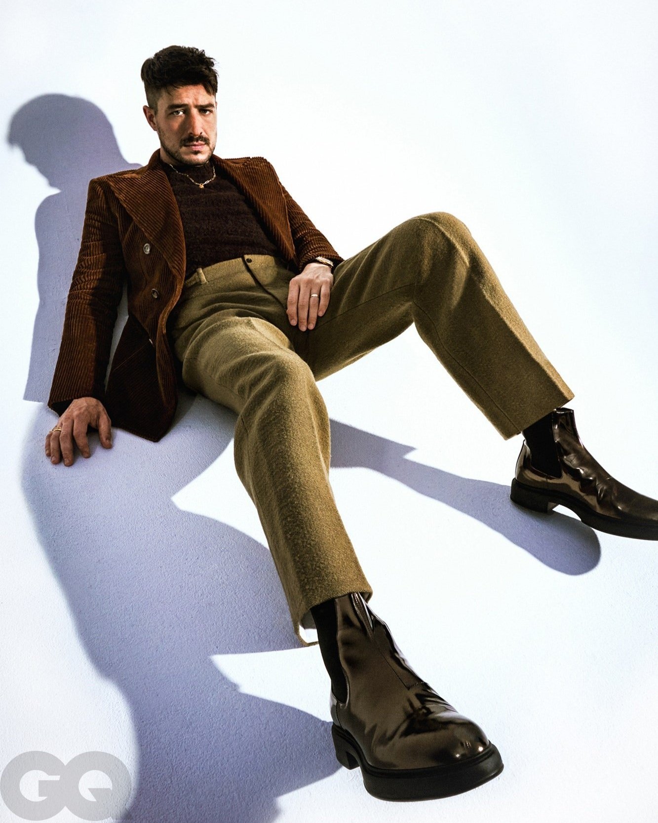 Marcus Mumford lying on a white floor looking at the camera.